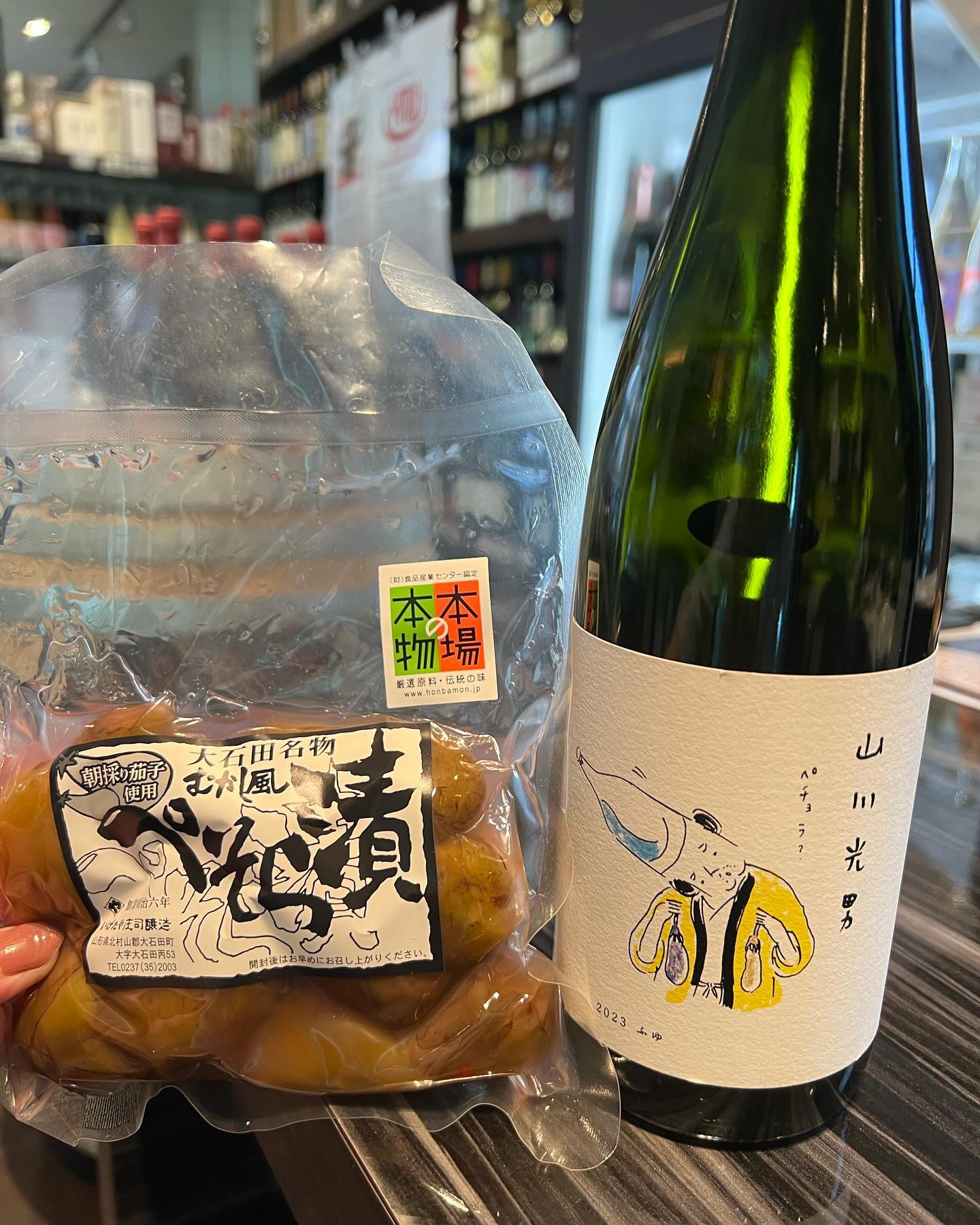 白いラベルの日本酒の瓶と袋詰めの漬物。